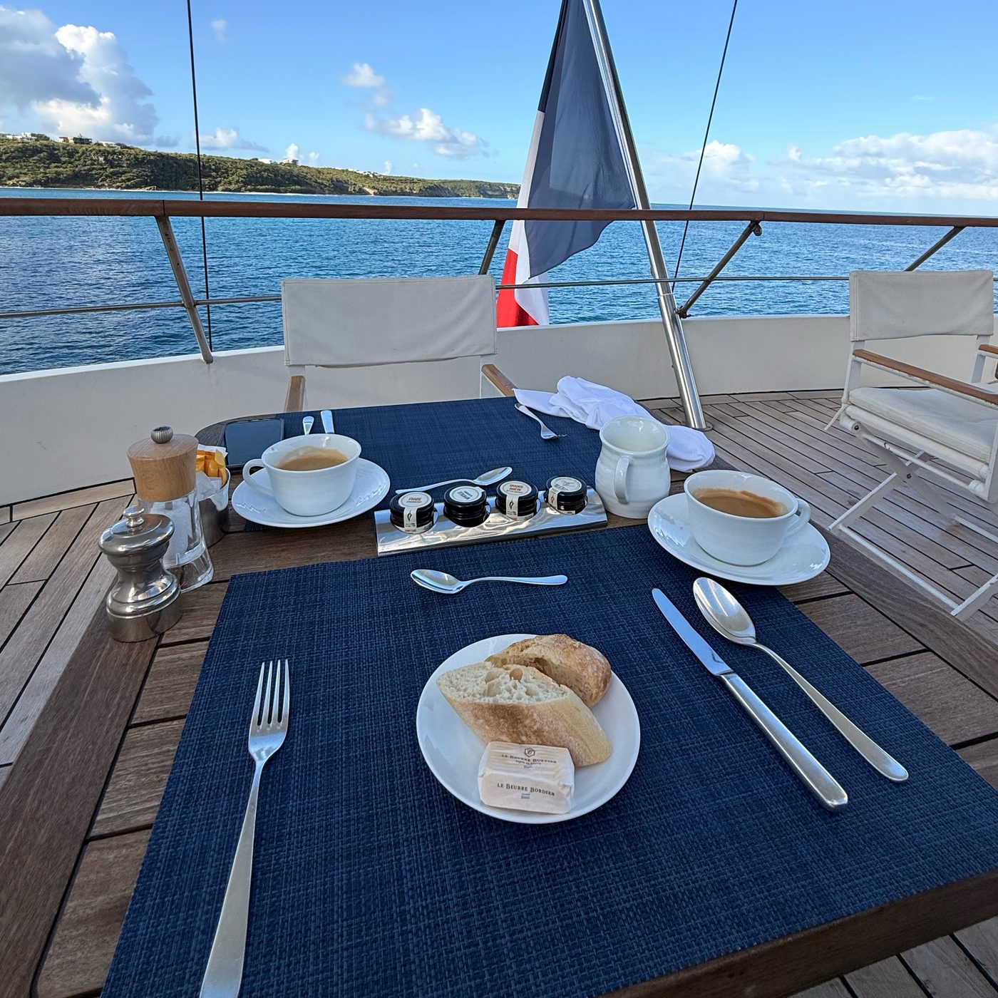 Breakfast table on the teak deck, with the French flag at the stern